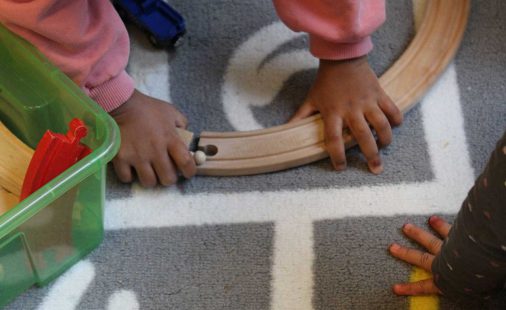 Kinder spielen mit Holzbahn